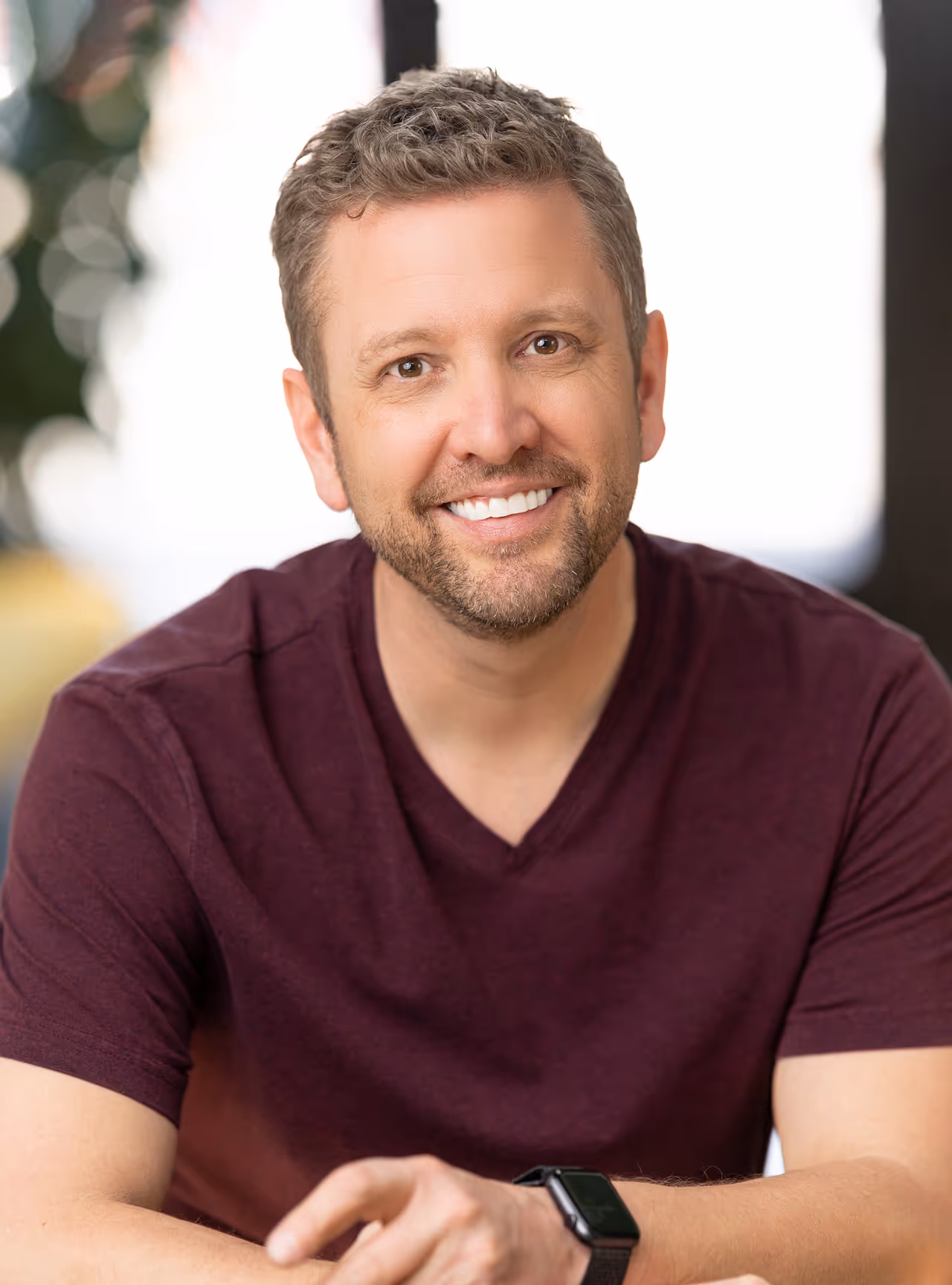 Chris' headshot smiling into the camera in a burgundy t-shirt