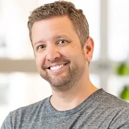 Chris Riley headshot smiling into the camera in the grey t-shirt